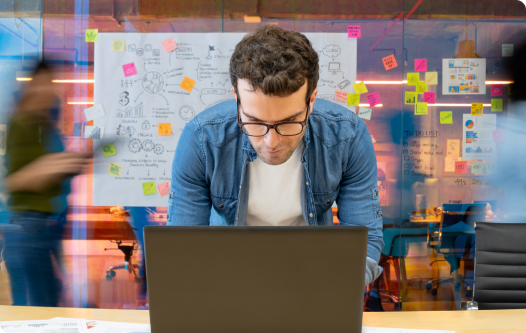 Man with glasses looking down at laptop